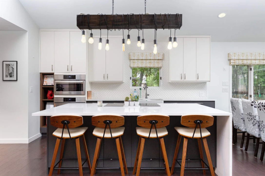 White kitchen design hanging lights and brown stools